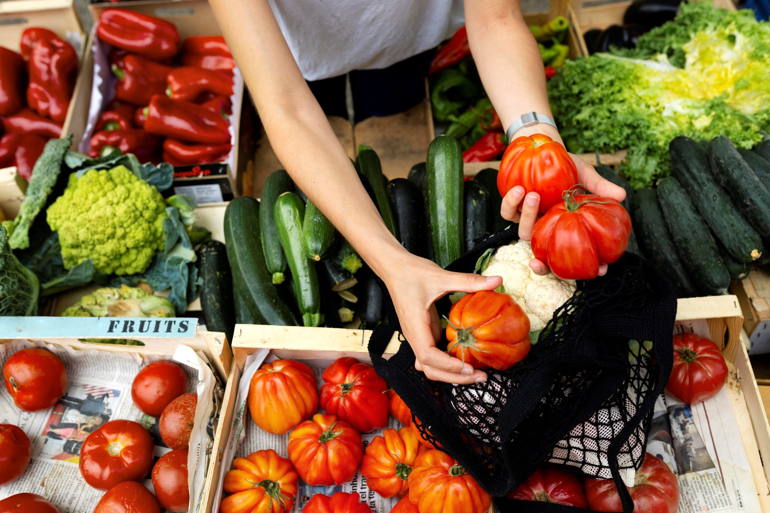 Closeup of woman holding vegetables llustrates blog "What Is Wholesale Produce?"