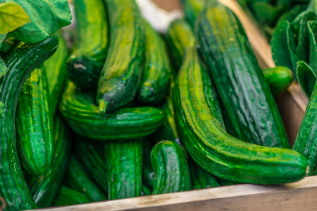 high-angle-view-cucumbers-crate-sale fresh Persian cucumbers on grocery display
